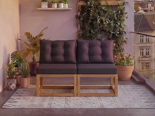 To-personers modul&aelig;r tr&aelig;sofa med m&oslash;rkegr&aring; puder p&aring; en altan omgivet af potteplanter og en bybaggrund