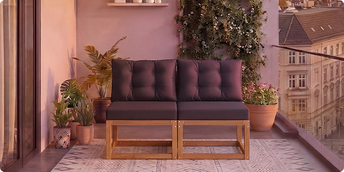 To-personers modulær træsofa med mørkegrå puder på en altan omgivet af potteplanter og en bybaggrund