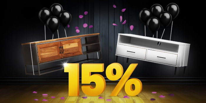 TV-konsol i træ og metal og hvid tv-konsol med sorte balloner foran et lyst gult 15%-skilt på mørkt trægulv.